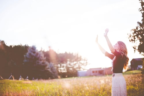 Woman in grassland looking at blue skies