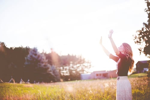 Woman in grassland looking at blue skies