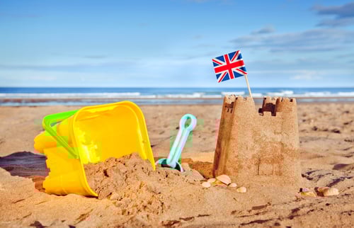 British Seaside traditional sand castle on the beach with bucket and spade shells and Union Jack Flag